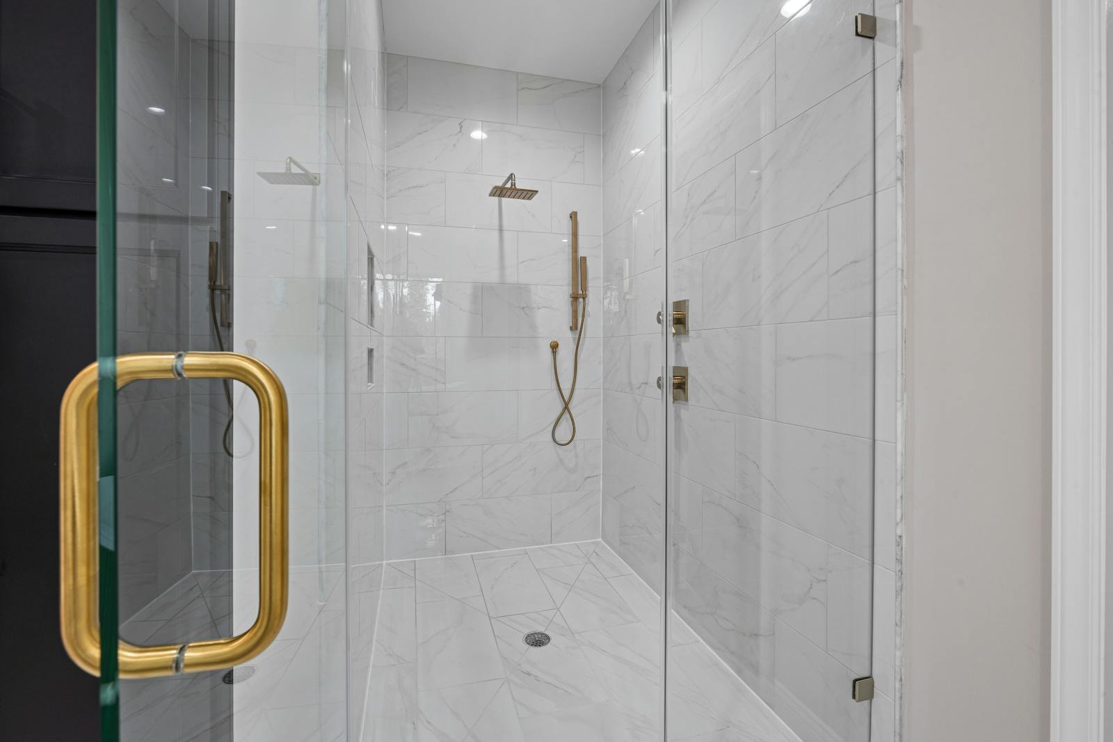 Elegant contemporary shower featuring marble tiles and gold fixtures.